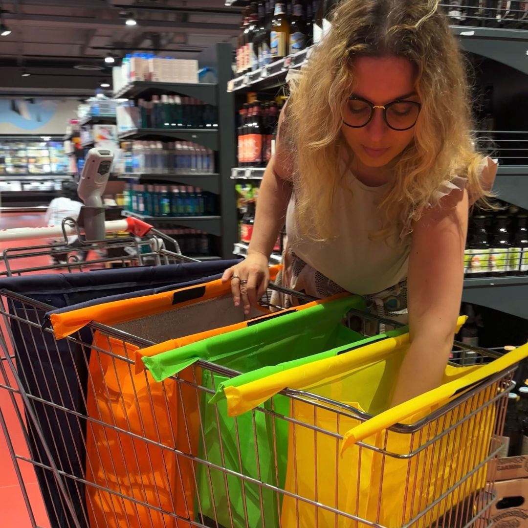 Donna che imbusta la spesa in una borsa Bustí aperta nel carrello al supermercato