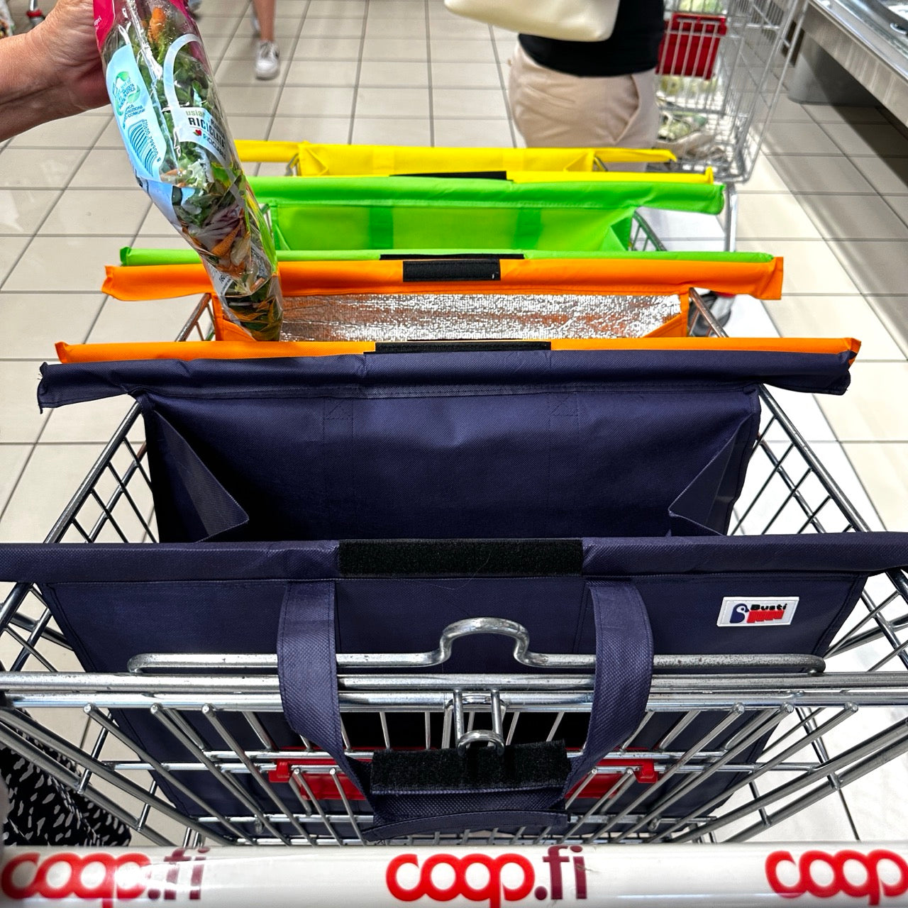 Mano che imbusta un’insalata in una borsa Bustí all’interno del carrello